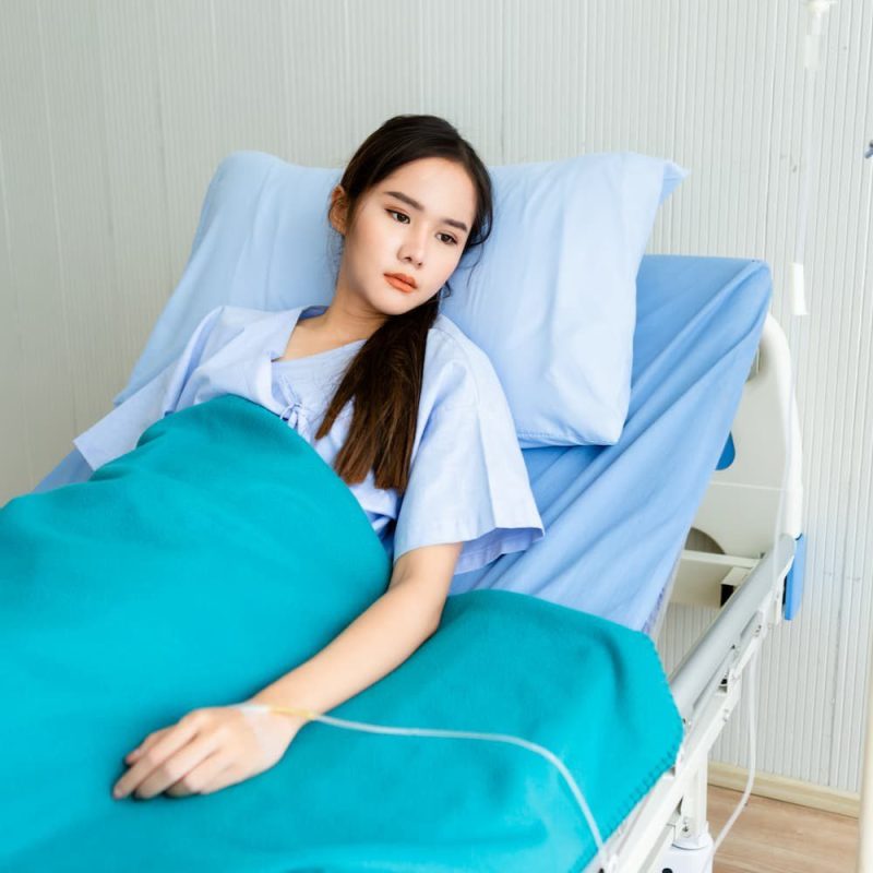 thoughtful-young-woman-lying-bed-hospital (1)